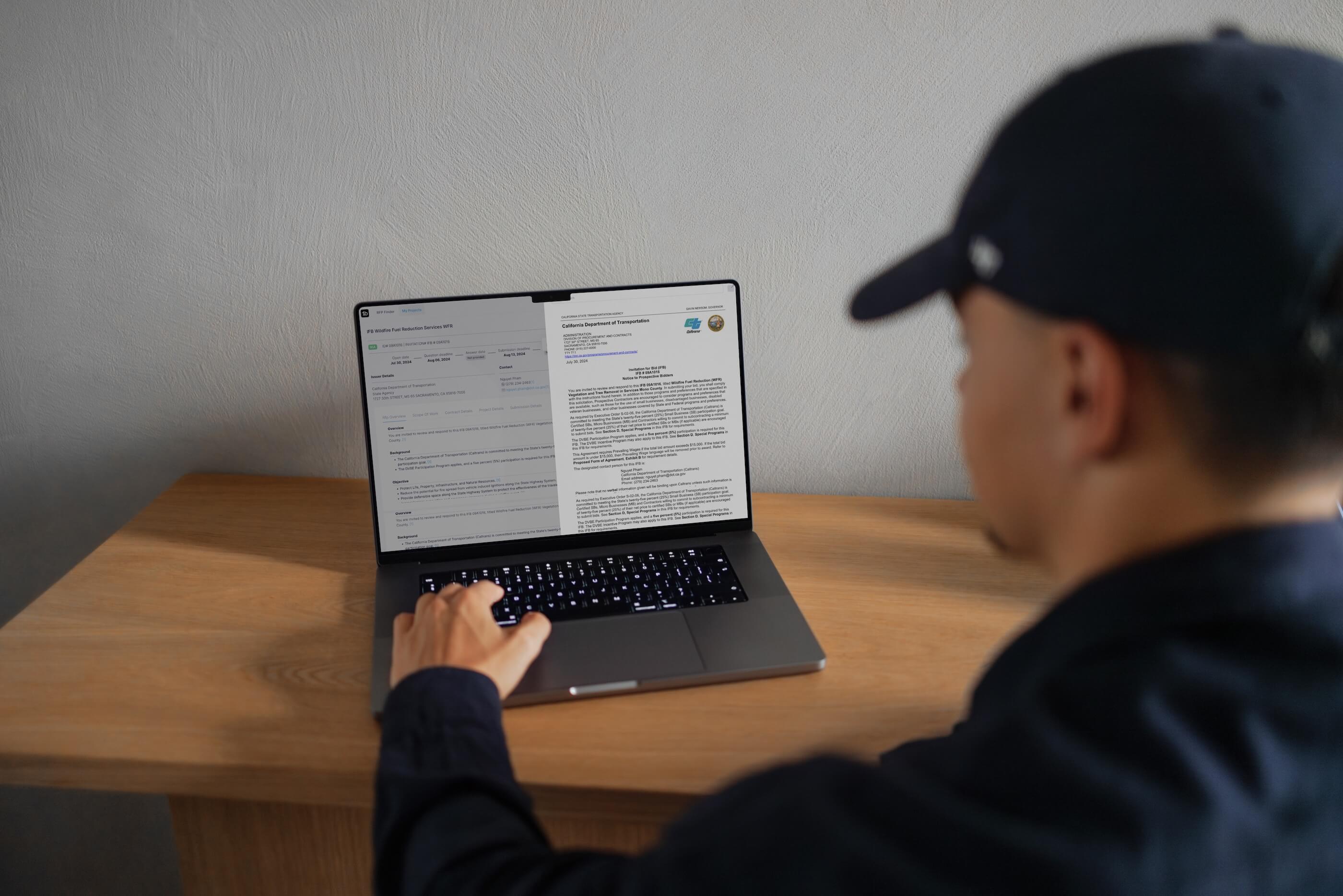 A man looking at a computer with the 1bid dashboard on it
